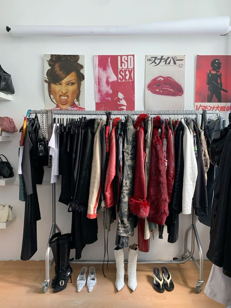 A clothing rack of curated garments below framed posters.